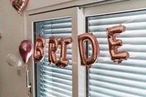 Bokstavsballonger i roséguld som stavar ordet BRIDE framför ett fönster.